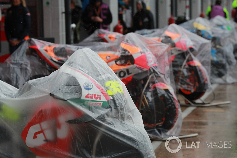 MotoGP-Bikes unter Regenplanen in der Boxengasse