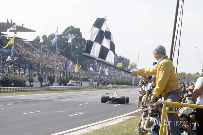 Juan Manuel Fangio sventola la bandiera a scacchi a Carlos Reutemann, Williams FW07C-Ford Cosworth