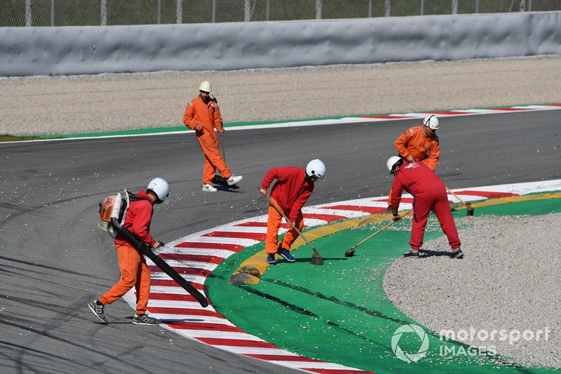 Marshals clear gravel from the track