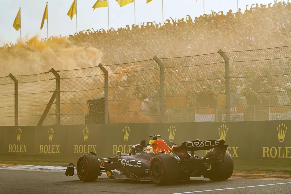 Max Verstappen, Red Bull Racing RB18, 1st position, waves from his cockpit as fans turn the air orange in celebration