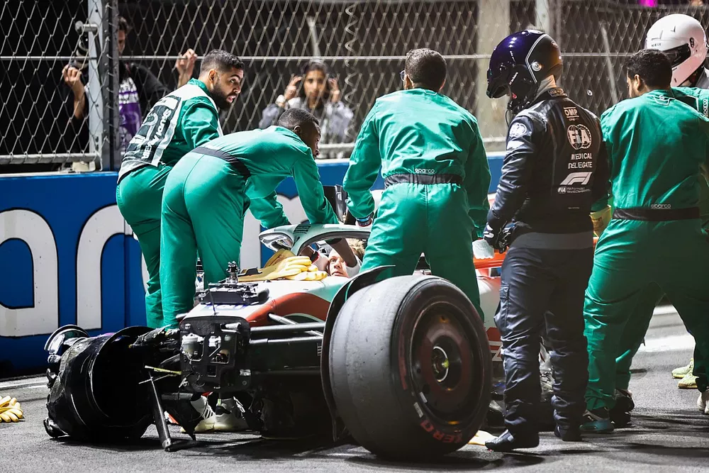 Les commissaires et les m&eacute;decins avec la monoplace d&eacute;truite de Mick Schumacher, Haas VF-22