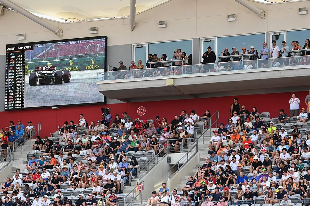 Fans in a grandstand next to a big screen