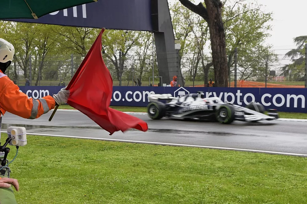 A marshal waves a red flag as Pierre Gasly, AlphaTauri AT03, passes