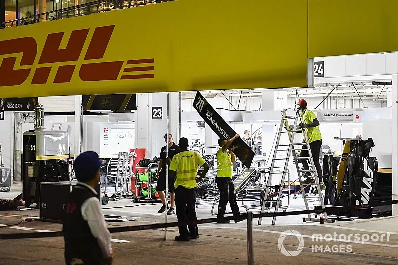 Teams clear equipment in the pit lane in anticipation of typhoon storms on Saturday