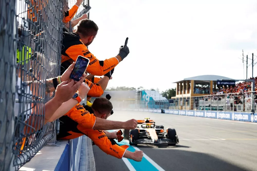 Lando Norris, McLaren MCL38, 1st position, crosses the line to cheers from his team on the pit wall