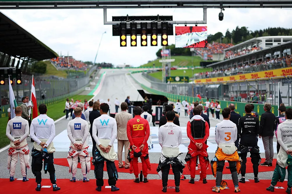 The drivers stand in line on the grid for the national anthem prior to the start