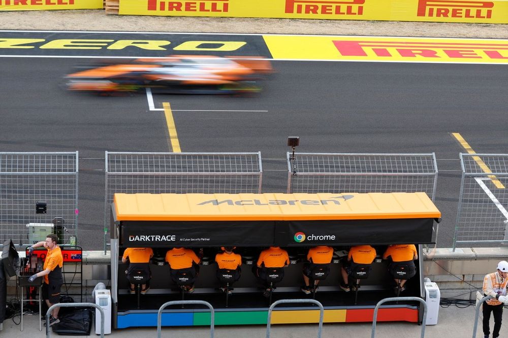 Oscar Piastri, McLaren MCL38, passes on track as team members of McLaren work on the pit wall