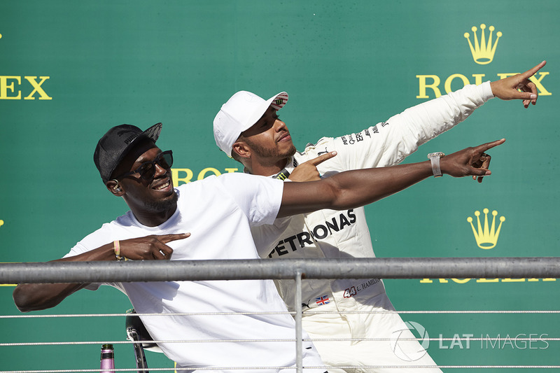Usain Bolt performs his trademark lightning bolt pose with race winner Lewis Hamilton, Mercedes AMG F1, on the podium