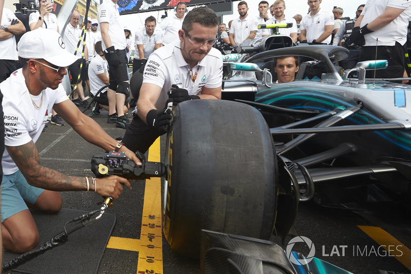 Lewis Hamilton, Mercedes AMG F1, tries his hand with a wheelgun on the car of his team mate