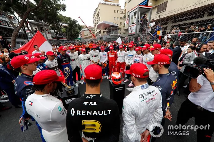 Pilotos en un minuto de silencio con gorra roja en homenaje a Niki Lauda