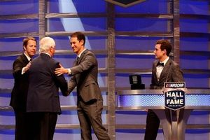 Brad Keselowski, Joey Logano y Ryan Blaney hablan en el escenario mientras Roger Penske es incluido en el Salón de la Fama de NASCAR