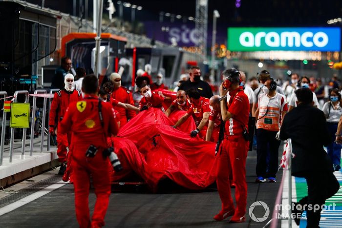 Los mecánicos de Ferrari con el coche dañado de Charles Leclerc, Ferrari SF21, en el pit lane