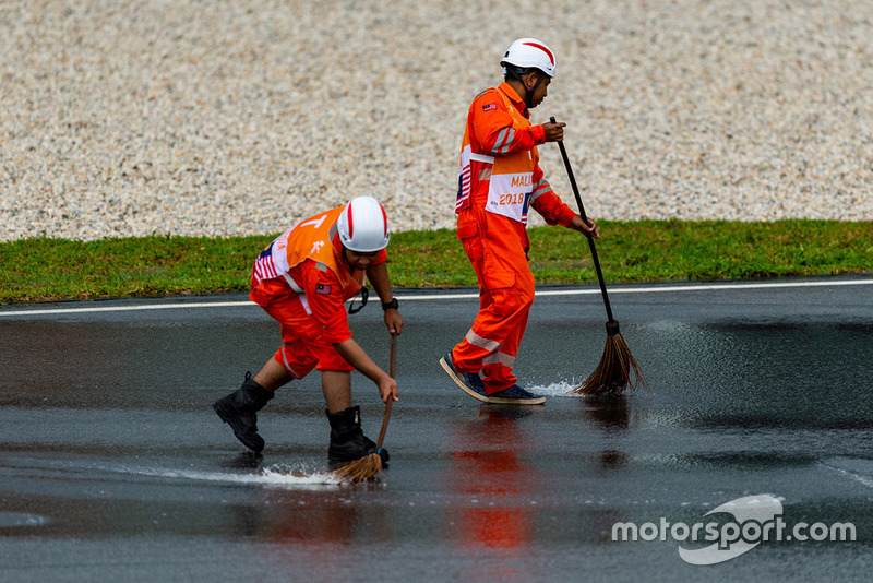 Les commissaires balaient la pluie sur la piste