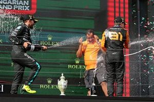 Lewis Hamilton, Mercedes-AMG F1 Team, 3ª posición, Oscar Piastri, McLaren F1 Team, 1ª posición, el delegado de trofeos de McLaren rocía champán en el podio.