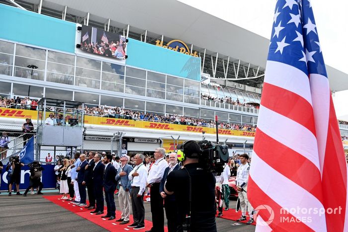 Dignatarios y pilotos se sitúan en la parrilla de salida para escuchar el himno nacional antes de la salida
