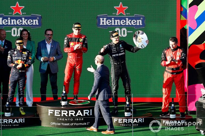 Sergio Pérez, Red Bull Racing, segundo, Charles Leclerc, Ferrari, primero, George Russell, Mercedes-AMG, tercero, y el representante de Ferrari en el podio