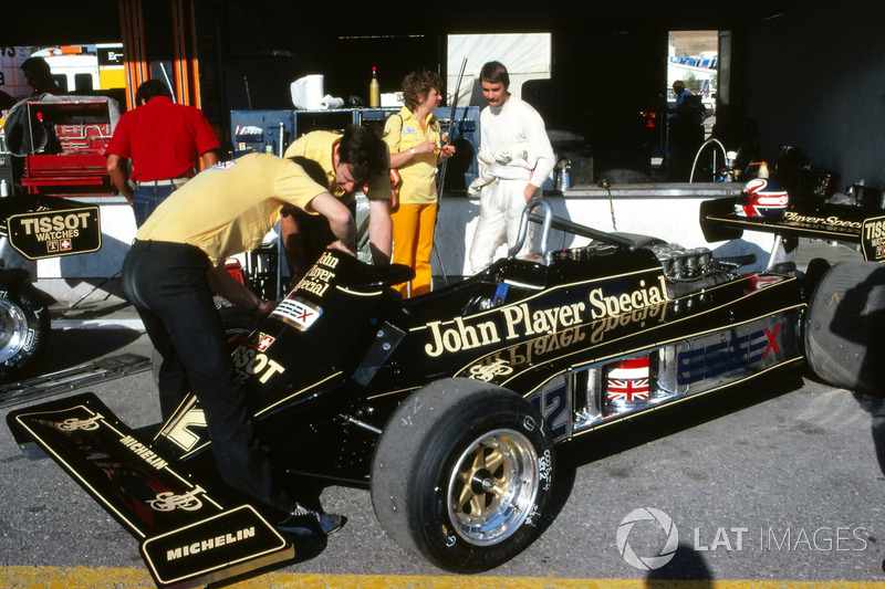 Nigel Mansell, habla con su esposa Roseanne Mansell, mientras los mecánicos trabajan en su Lotus 87 en el área del pit