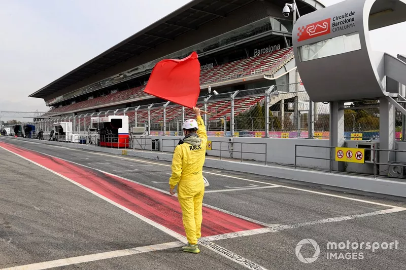 Un commissaire agite le drapeau rouge à la sortie de la voie des stands