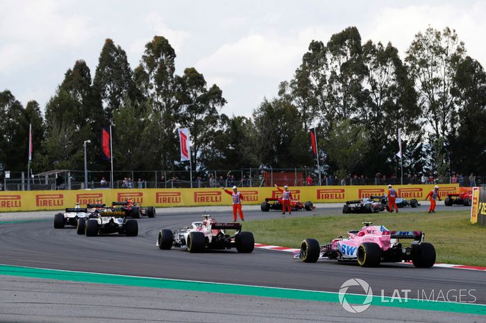 Los oficiales guían a los pilotos, incluidos Esteban Ocon, Force India VJM11 alrededor de escombros de un accidente en la vuelta de apertura