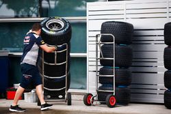 A Red Bull team member wheels a stack of Pirelli tyres