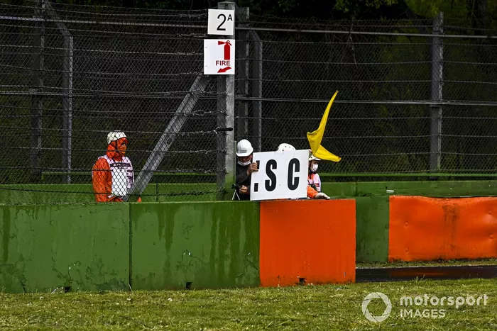 Los oficiales de pista despliegan el tablero del Safety Car y la bandera amarilla