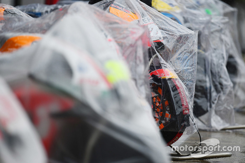 MotoGP-Bikes unter Regenplanen in der Boxengasse