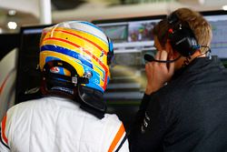 Fernando Alonso, McLaren, talks with his engineer in the garage