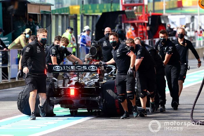 Los mecánicos mueven el coche de Lewis Hamilton, Mercedes W12, en el pit lane