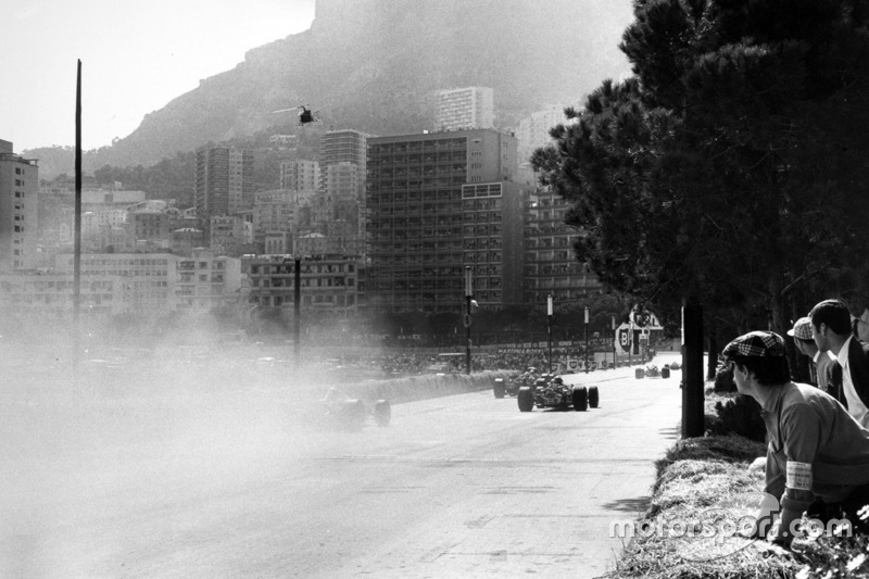 Los coches pasan por el humo del accidente de Lorenzo Bandini, Ferrari 312