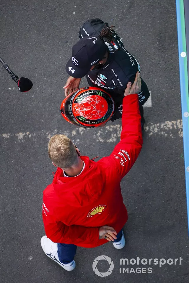 Mick Schumacher, Alfa Romeo Racing, entrega al ganador de la carrera Lewis Hamilton, Mercedes-AMG F1, el casco Mercedes de su padre, Michael Schumacher de 2012