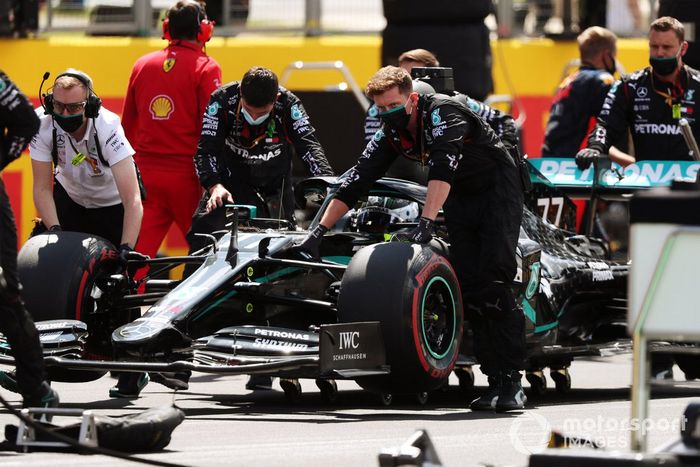 Los mecánicos posicionan a Valtteri Bottas, Mercedes F1 W11, en su lugar en la parrilla