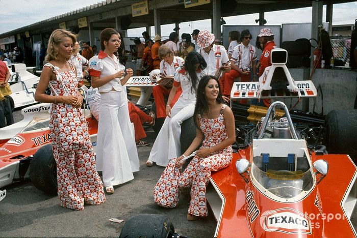 Chicas Marlboro y mecánicos McLaren con McLaren M23 Fords en los fosos