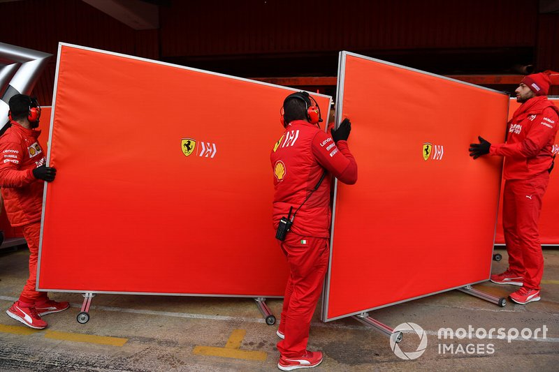 Des mécaniciens Ferrari avec des caches devant le garage