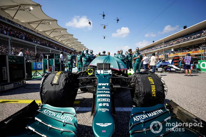 Miembros del equipo Aston Martin en la parrilla de salida con el coche de Lance Stroll, Aston Martin AMR21, mientras un quinteto de helicópteros del ejército estadounidense sobrevuela la parrilla de salida