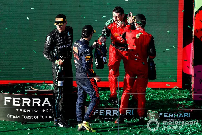 Sergio Pérez, Red Bull Racing, segundo, Charles Leclerc, Ferrari, primero, George Russell, Mercedes-AMG, tercero, y el representante de Ferrari celebran en el podio