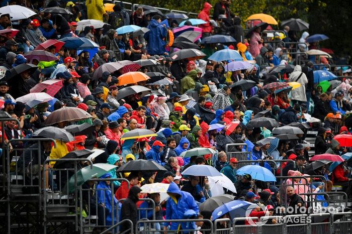 Fans in the grandstand with umbrellas in the rain