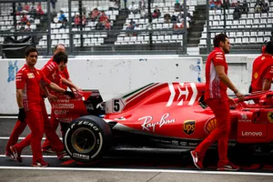 Des mécaniciens Ferrari déplacent la monoplace de Sebastian Vettel, Ferrari SF71H, dans la voie des stands