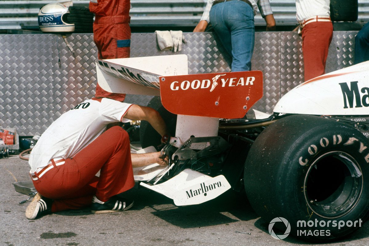 A mechanic works on the rear of the car of Jochen Mass,  McLaren M23 Ford