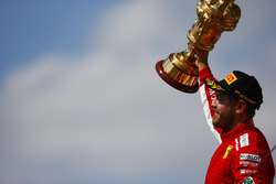 Sebastian Vettel, Ferrari, celebrates victory on the podium, and raises his trophy