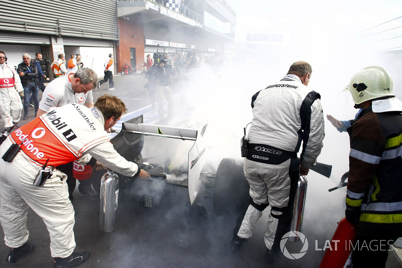 McLaren mechanics help extinguish the fire on Rubens Barrichello, Brawn GP BGP001 Mercedes at Parc Ferme
