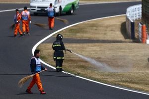 Un bombero rocía la hierba del lateral de la pista para humedecerla tras los incendios ocurridos durante los entrenamientos finales.