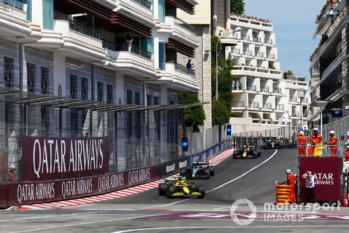 Los comisarios ondean las banderas amarillas en la primera vuelta mientras Lando Norris, McLaren MCL38, George Russell, Mercedes F1 W15, Max Verstappen, Red Bull Racing RB20