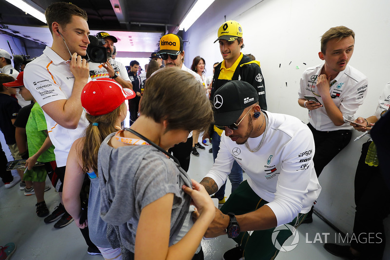 Lewis Hamilton, Mercedes AMG F1, signs a grid kid's short, as Carlos Sainz Jr., Renault Sport F1 Team, Fernando Alonso, McLaren and Stoffel Vandoorne, McLaren, look on