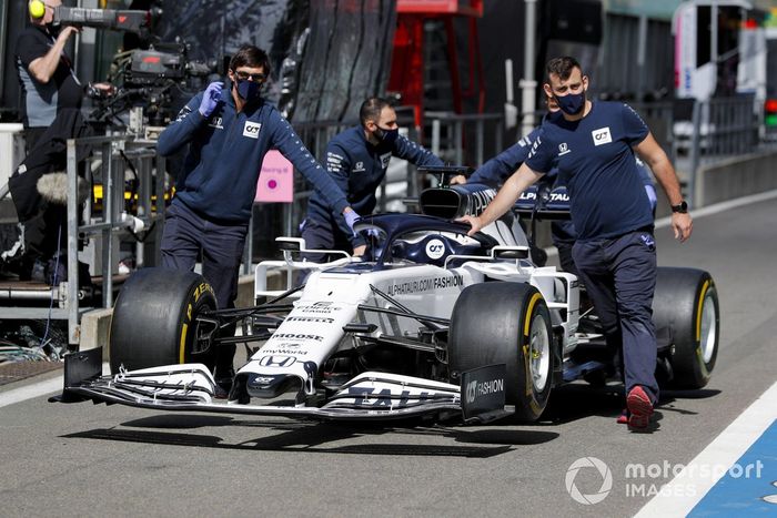 Los mecánicos de AlphaTauri empujan el AlphaTauri AT01 por el pit lane