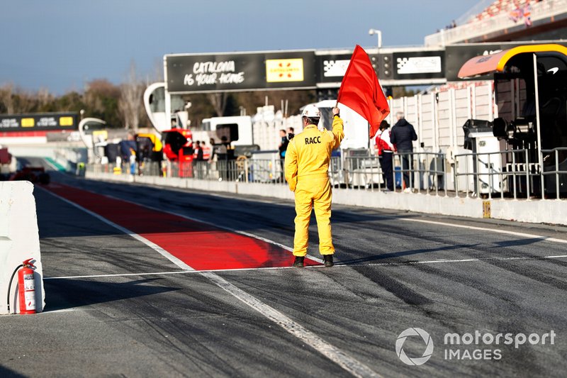 Un commissaire agite le drapeau rouge dans la voie des stands