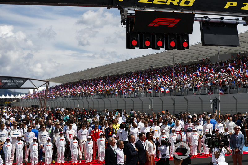 The drivers stand behind the Grid Kid mascots as the national anthem is sung prior to the start