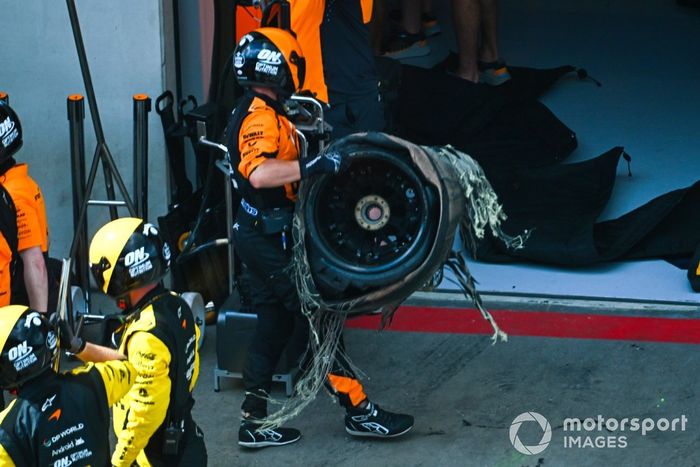 El neumático dañado es retirado del coche de Lando Norris, McLaren MCL38
