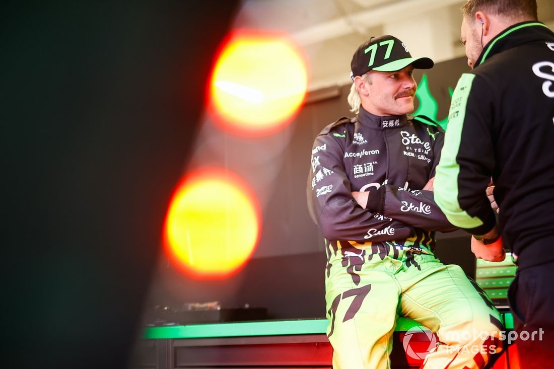 Valtteri Bottas, da Stake F1 Team KICK Sauber, fala com um colega de equipa na garagem
