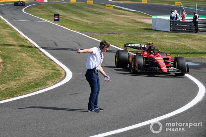 Un miembro del personal de la FIA guía a Carlos Sainz, Ferrari SF-23, hacia el pit lane al final de la sesión de clasificación.