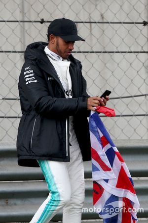 Lewis Hamilton, Mercedes AMG, toma la pista para entretener a los fans y recoge una bandera de la Un